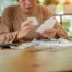 Person sitting at a wooden table sorting through receipts with a focused expression — illustrating the financial planning and debt review common in the context of deciding whether to file bankruptcy or divorce in Arizona.