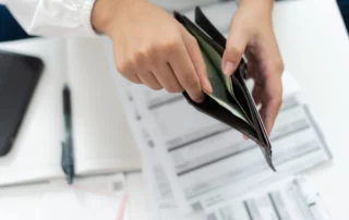 erson holding empty wallet over bills and documents, illustrating missed Chapter 13 bankruptcy payments in Arizona.