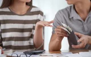 Couple discussing finances at a wooden table, comparing Chapter 13 bankruptcy and debt consolidation options for managing debt in Arizona.